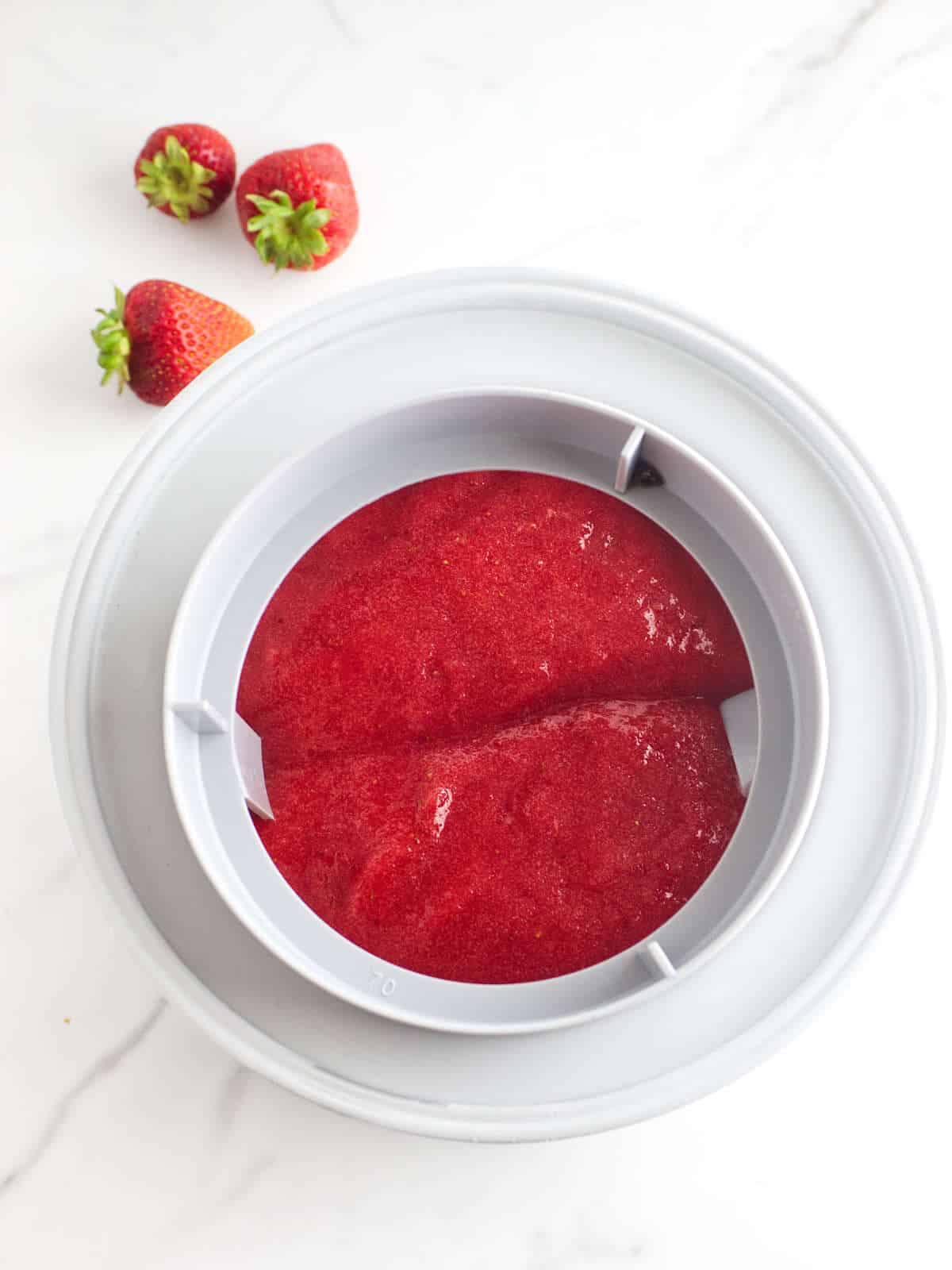 pureed strawberries poured into a frozen freezer bowl for processing.