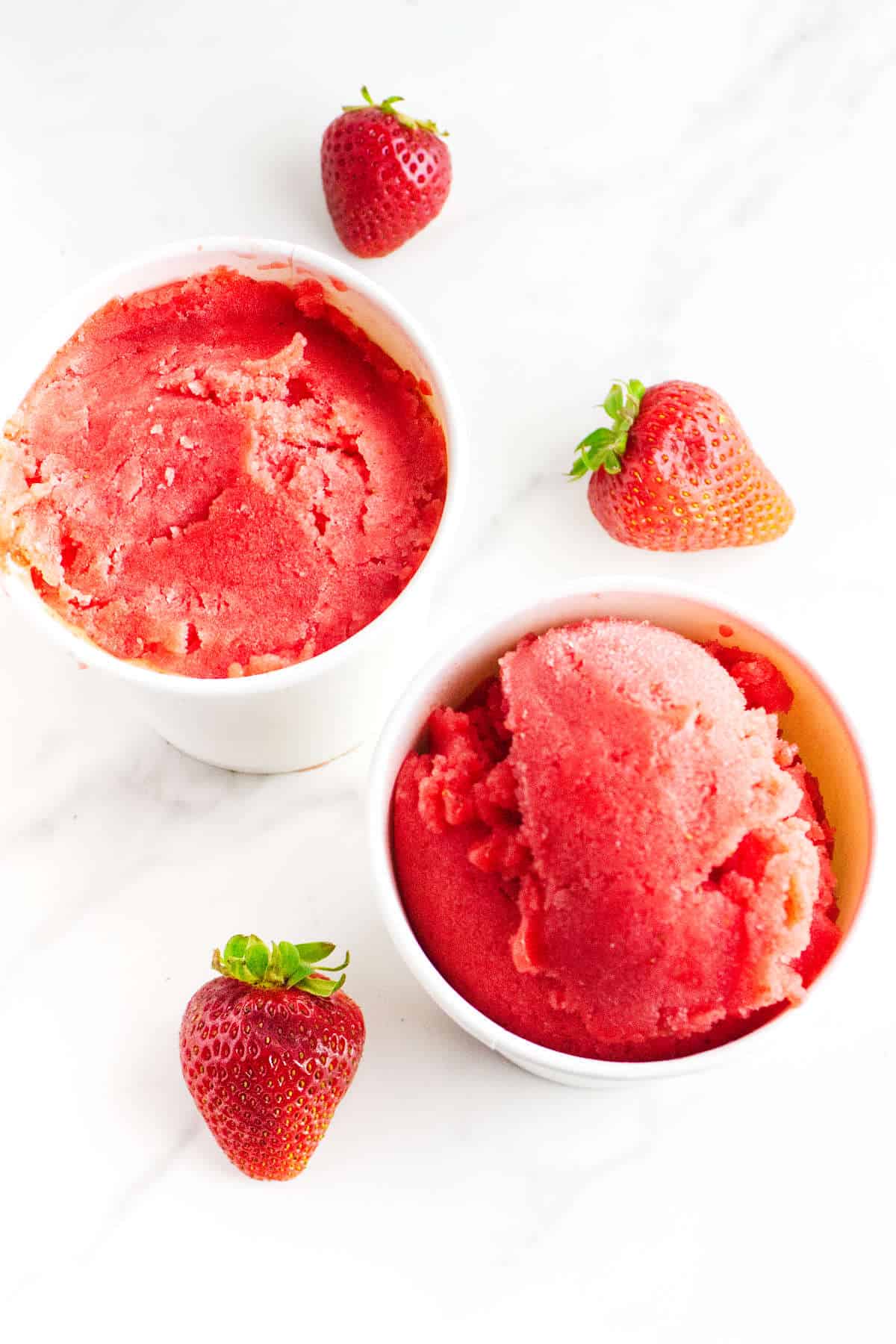 Strawberry sorbet in ice cream storage tubs.