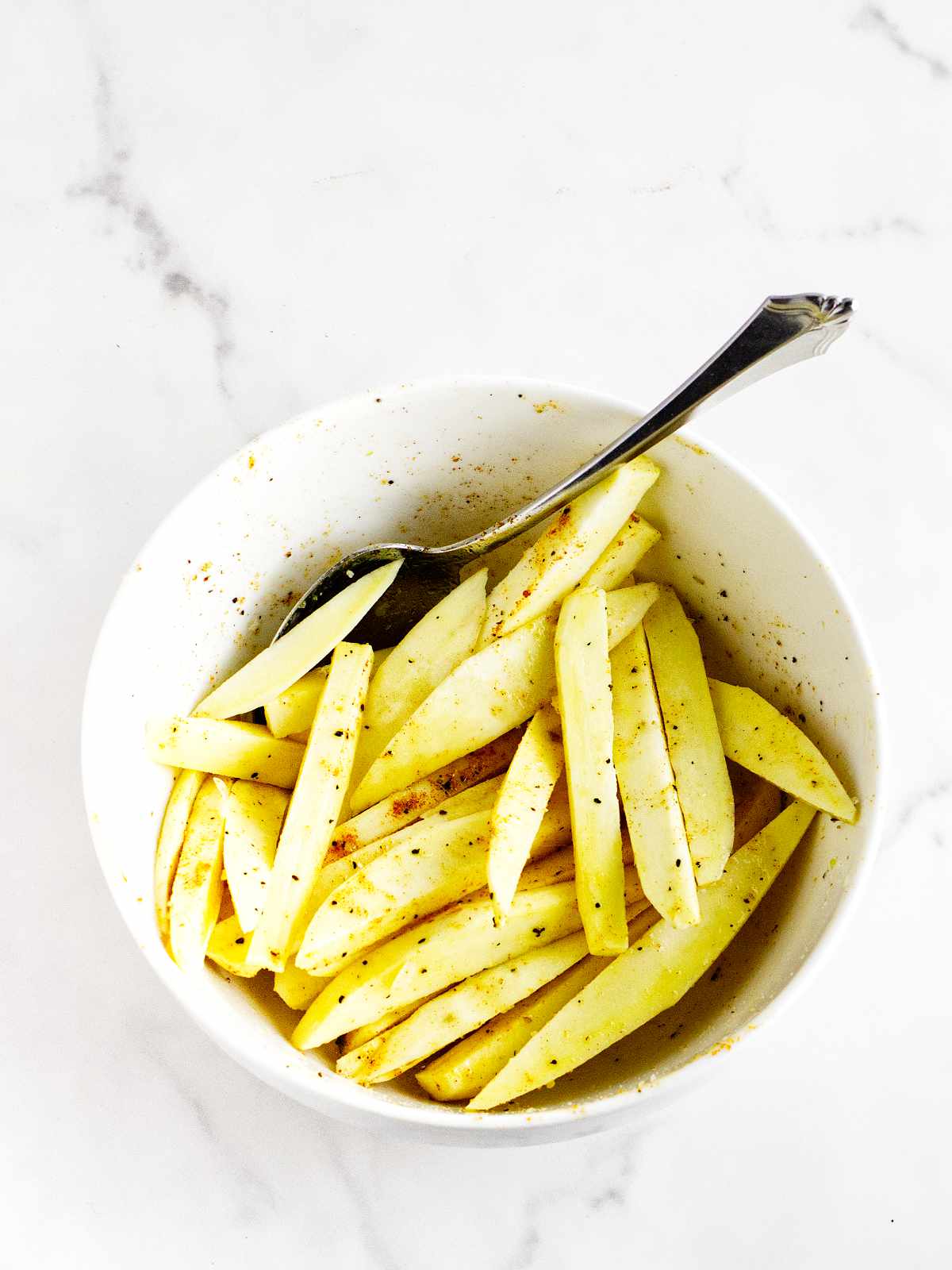 Bowl of seasoned freshly cut sweet potato fries.