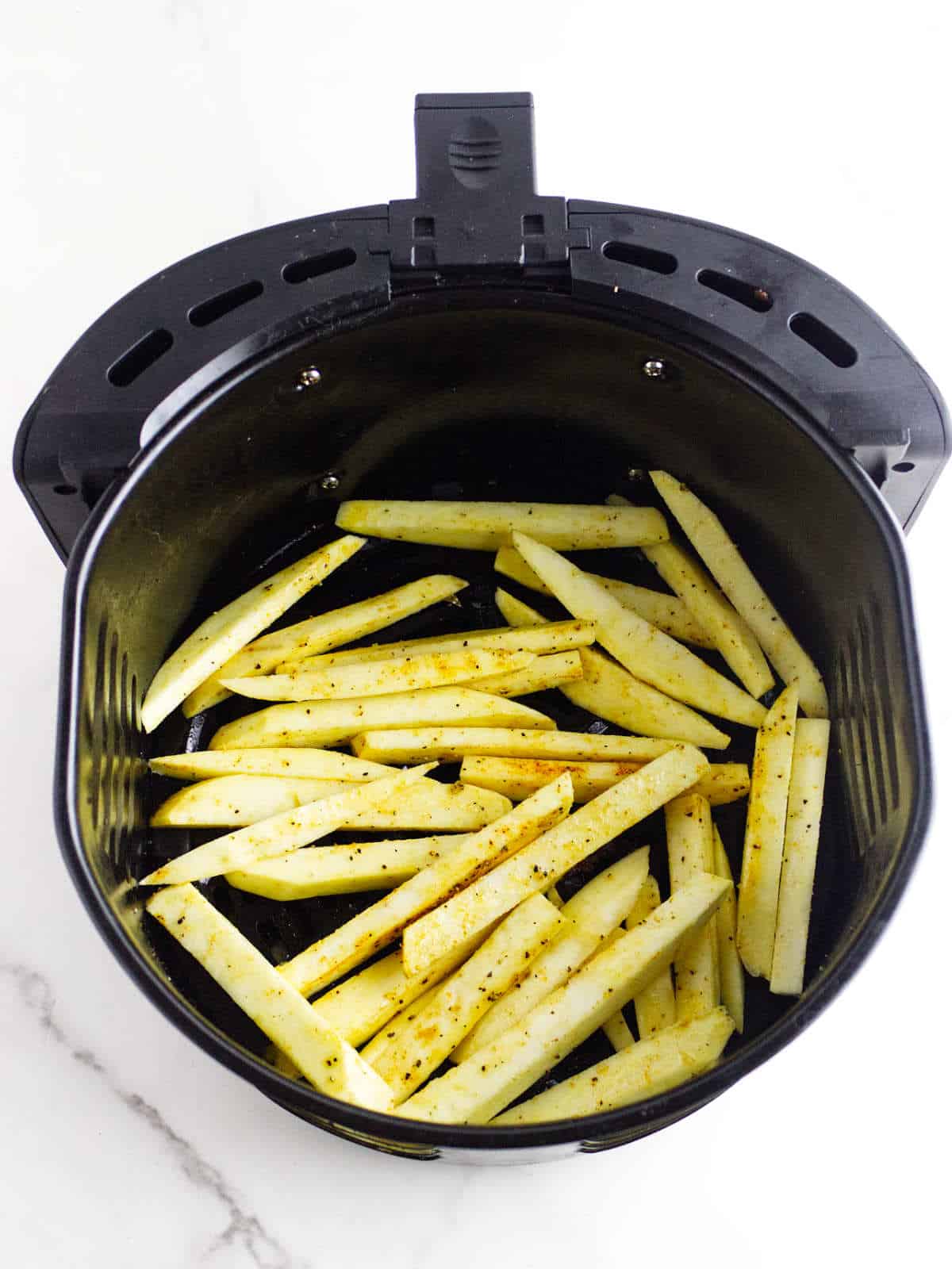 air fryer with seasoned raw white sweet potato fries.