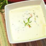 creamy wild rice soup garnished with rosemary.