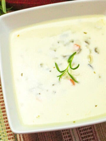 creamy wild rice soup garnished with rosemary.