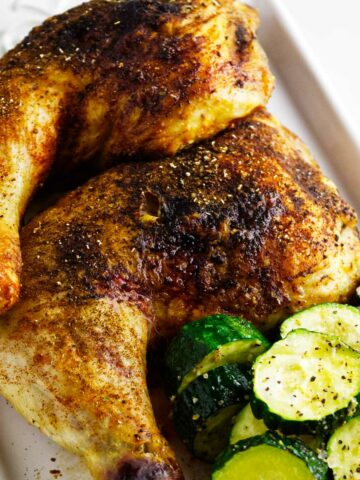 Serving platter with air fryer chicken leg quarters and some zucchini squash.