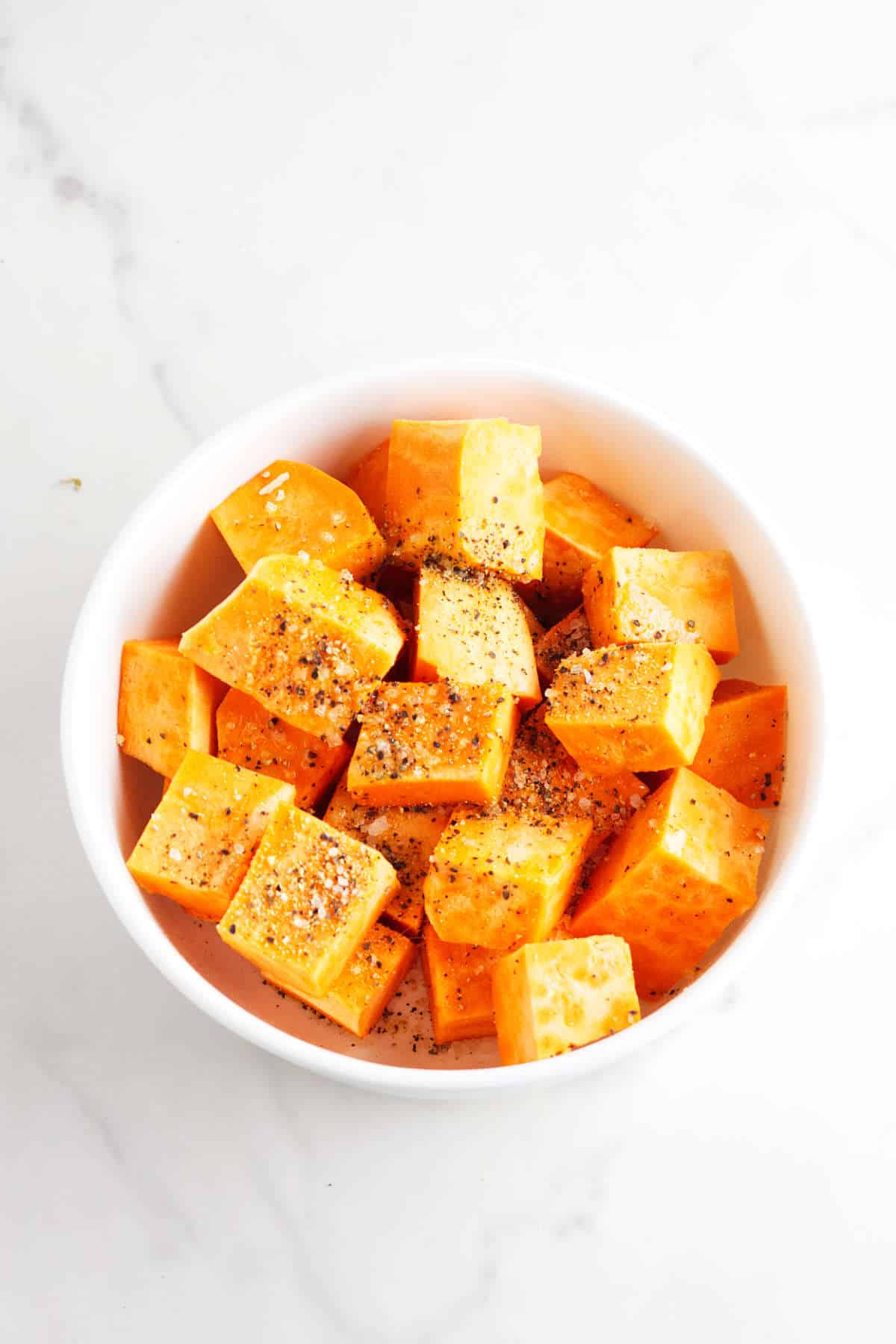 Seasoned sweet potato cubes in a bowl.