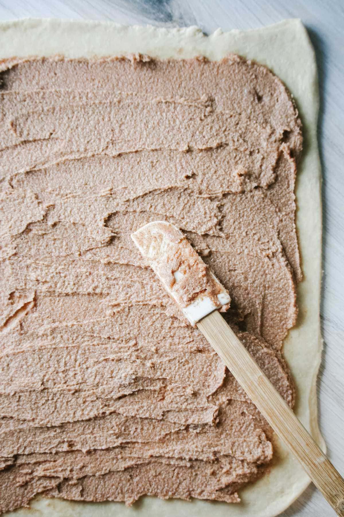 Cinnamon roll filling spread over dough.