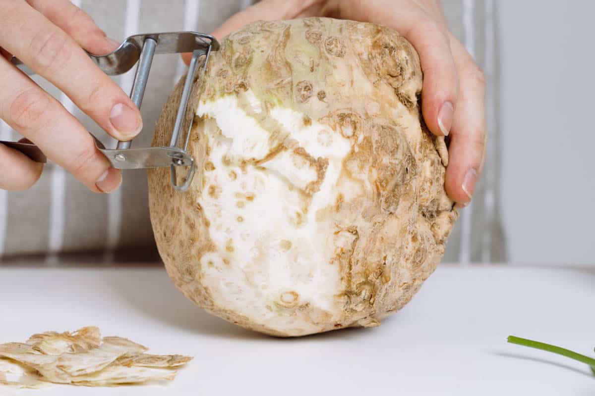 peeling celeriac or celery root with peeler.