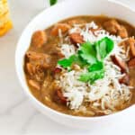 bowl of chicken and sausage gumbo with cornbread nearby.