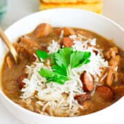 bowl of chicken and sausage gumbo with cornbread nearby.