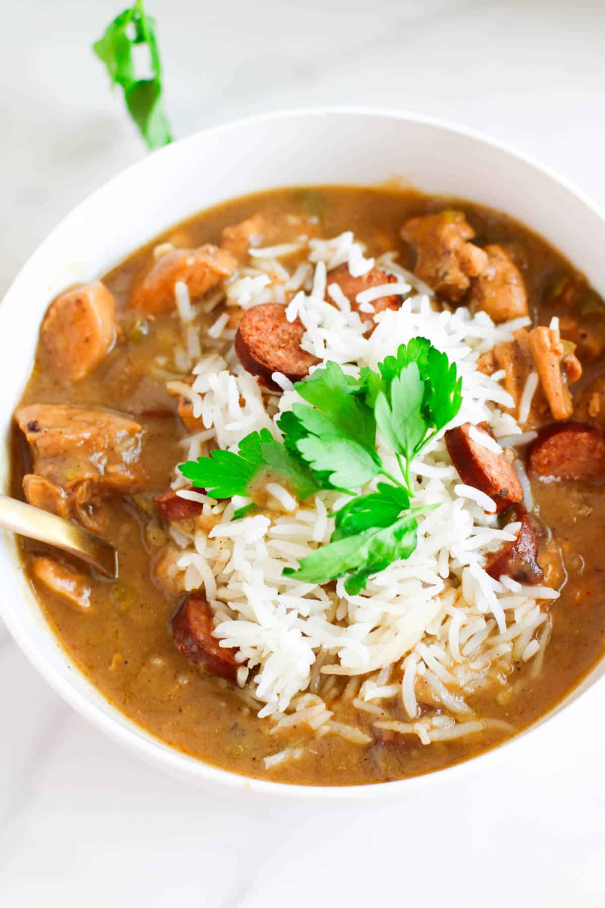 bowl of chicken and sausage gumbo with cornbread nearby.
