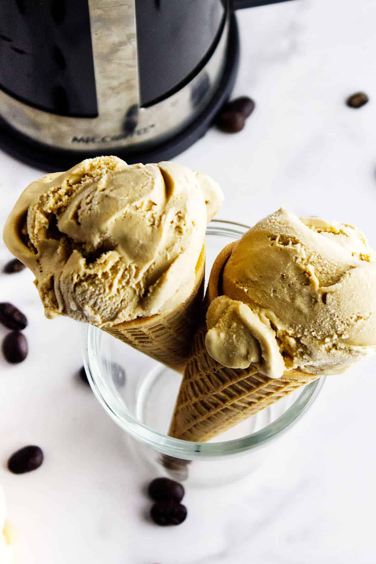 homemade coffee ice cream in cones with a French press in the background.