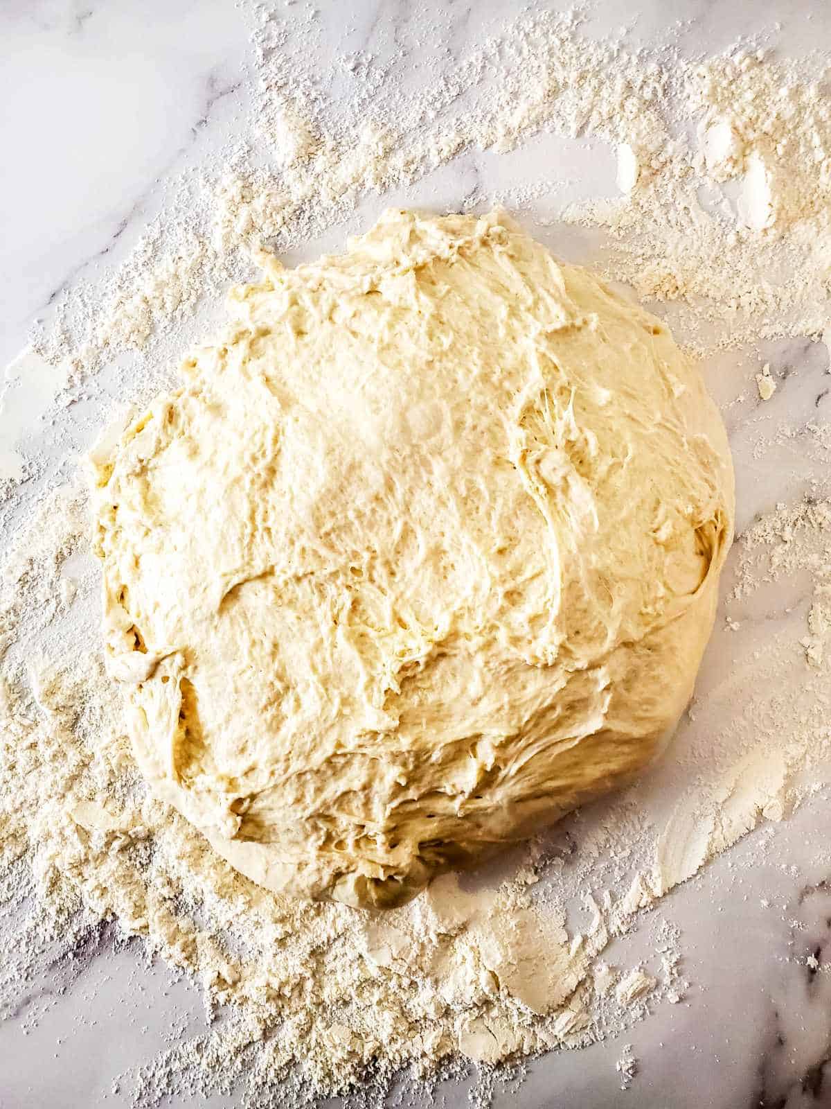 kneading bread dough on a floured surface.