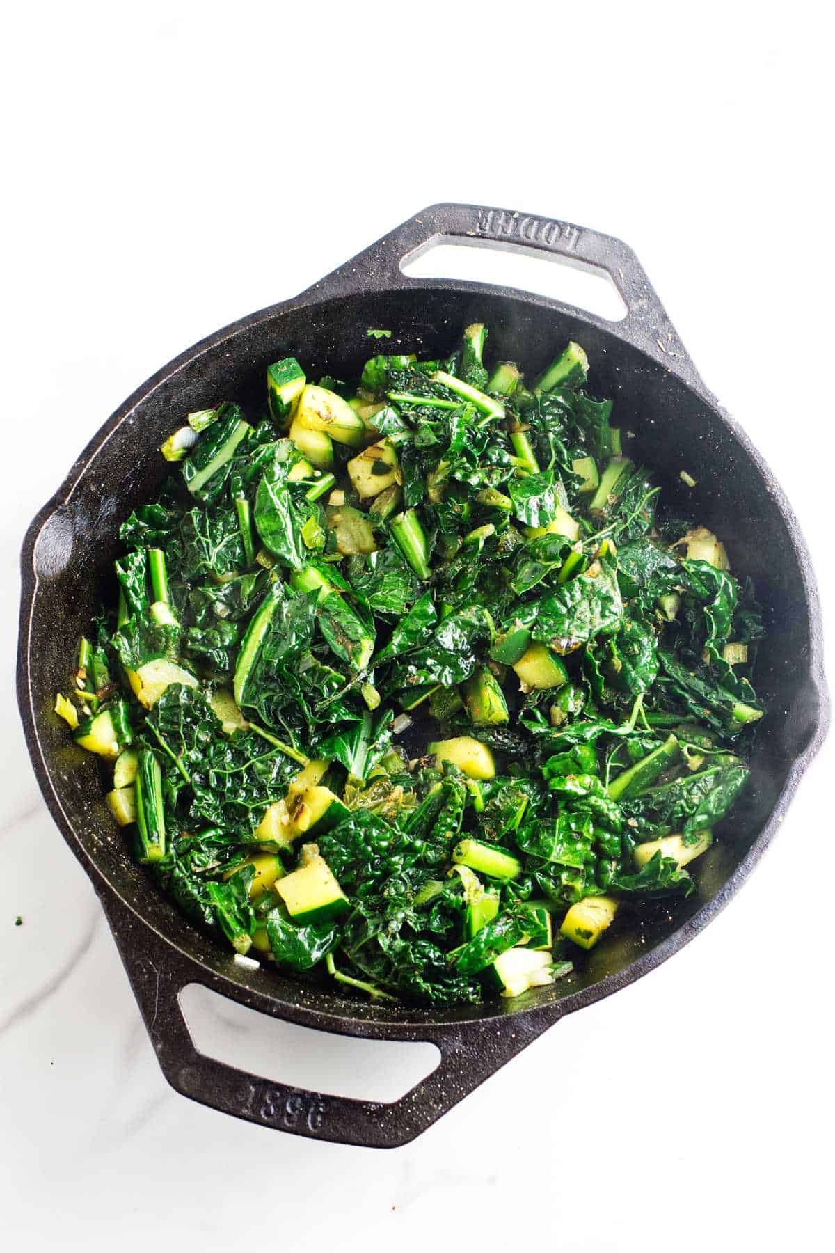 greens cooked down and simmering in a skillet.