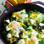 Skillet breakfast of eggs over simmered greens and goat cheese.