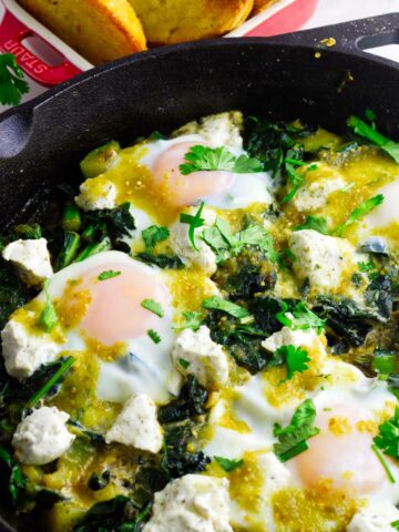 Skillet breakfast of eggs over simmered greens and goat cheese.