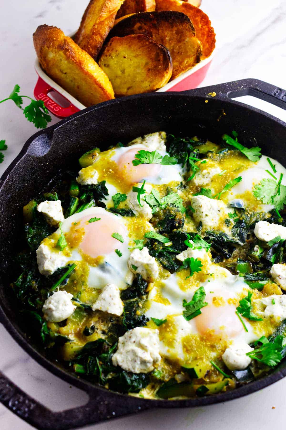 Skillet breakfast of eggs over simmered greens and goat cheese.