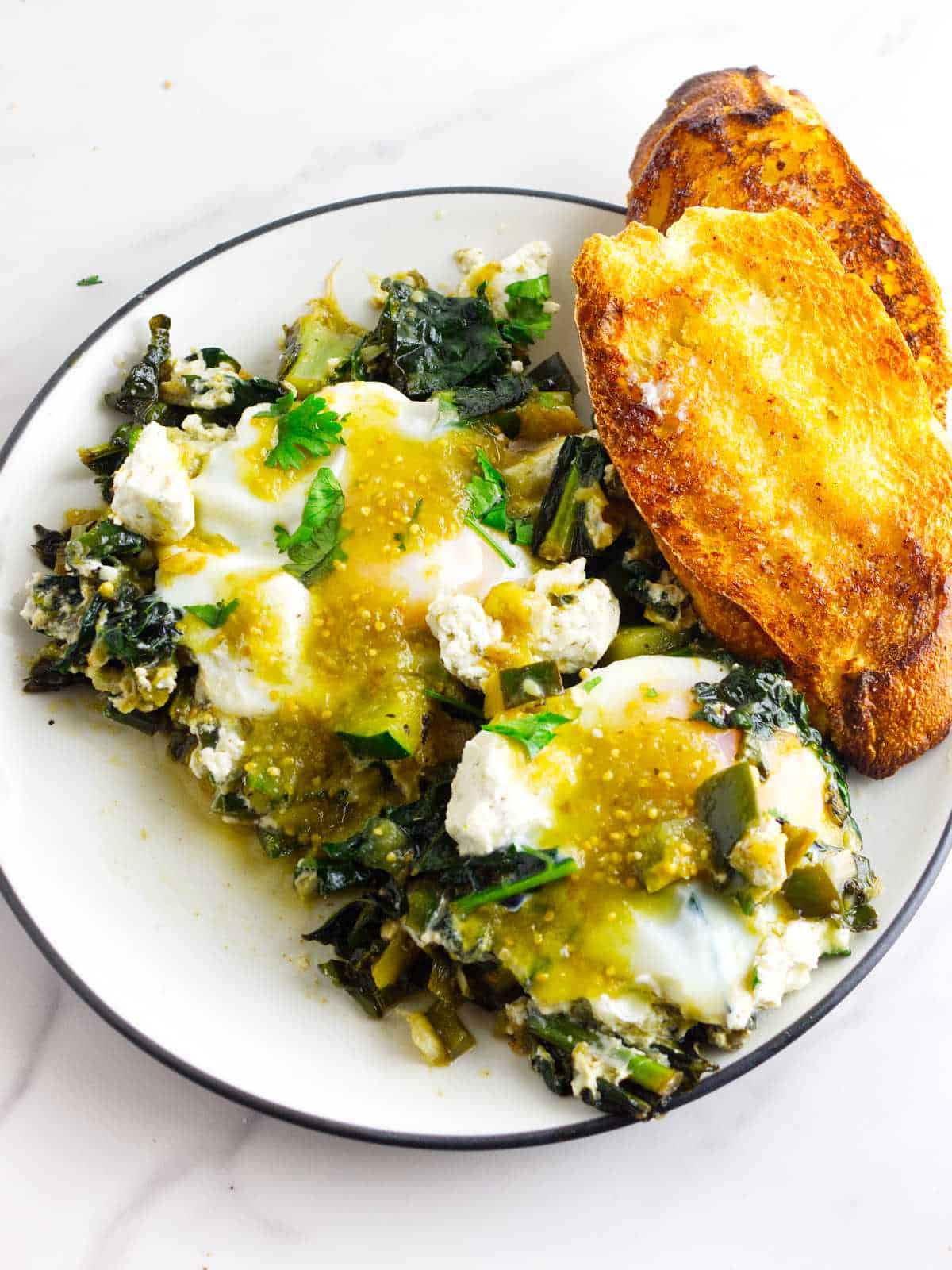 Verde sauce drizzled over a serving of green shakshuka, with toast points on the side.