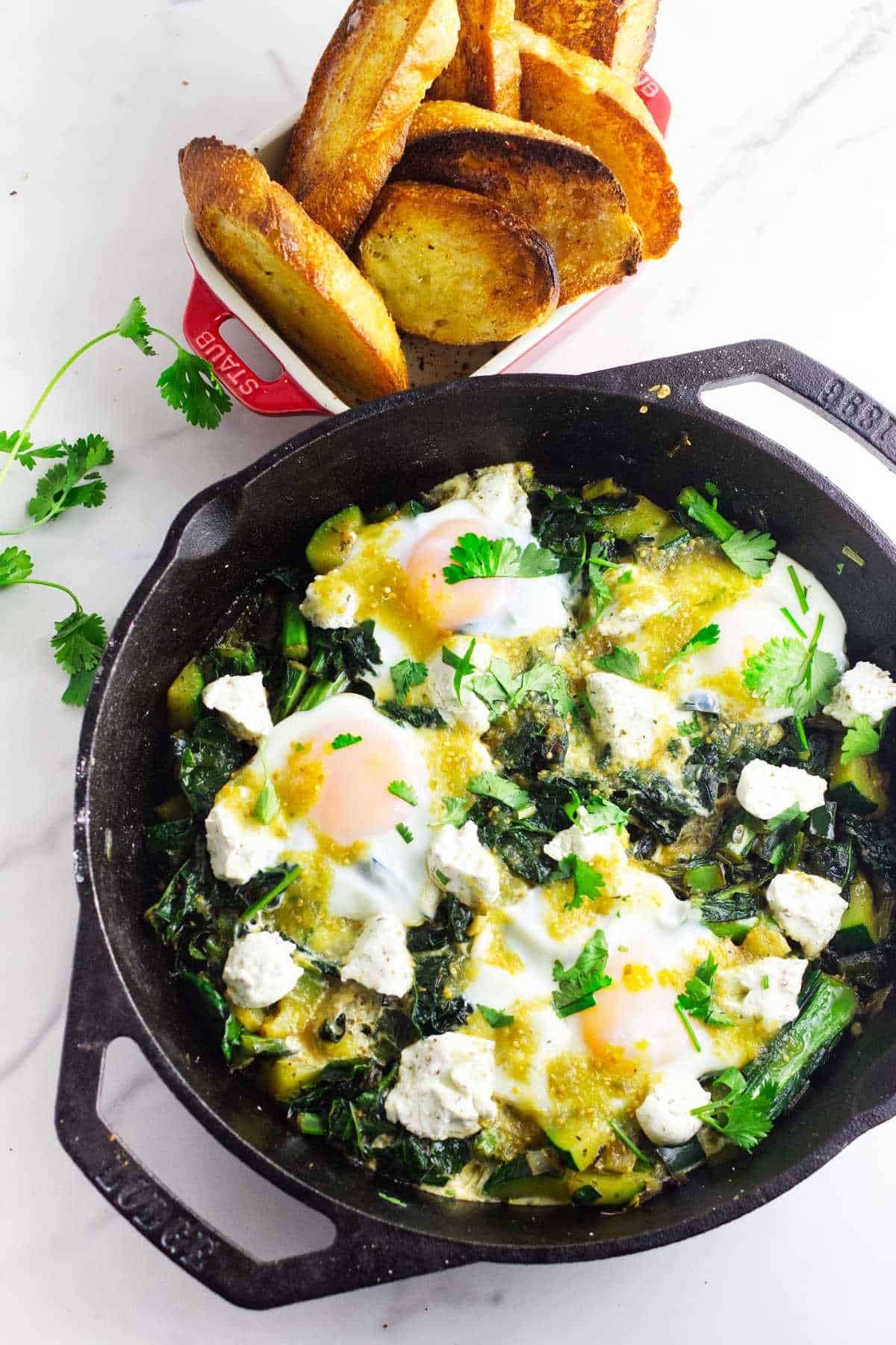 Skillet breakfast of eggs over simmered greens and goat cheese.