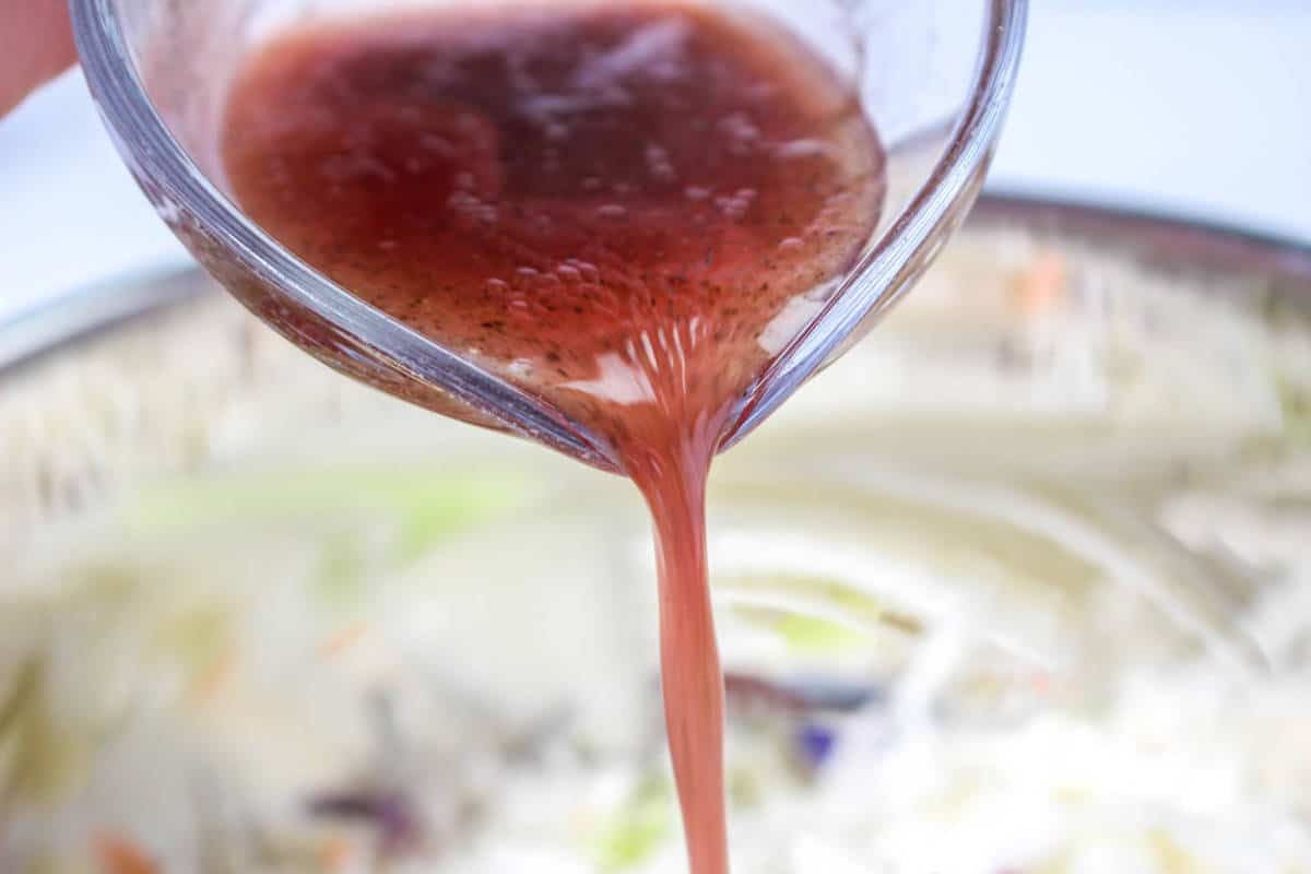 pouring red wine vinegar salad dressing over salad.
