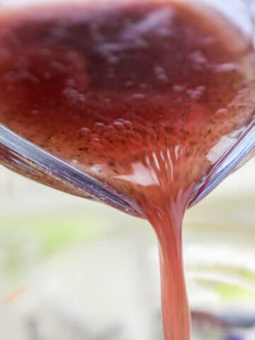 Red wine Italian vinaigrette being poured over salad.