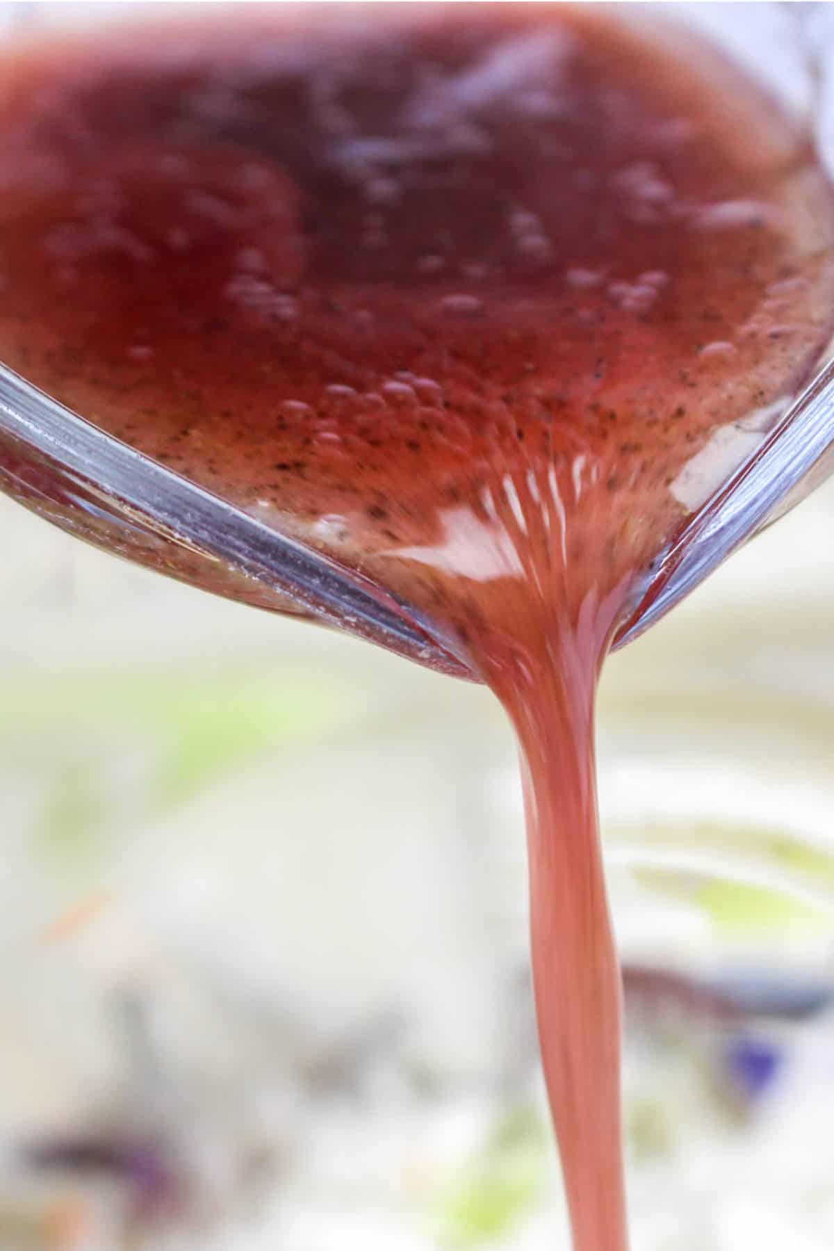 Red wine Italian vinaigrette being poured over salad.