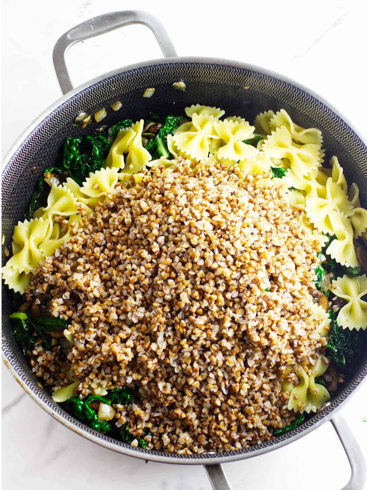 bowtie pasta and cooked kasha added to a skillet.