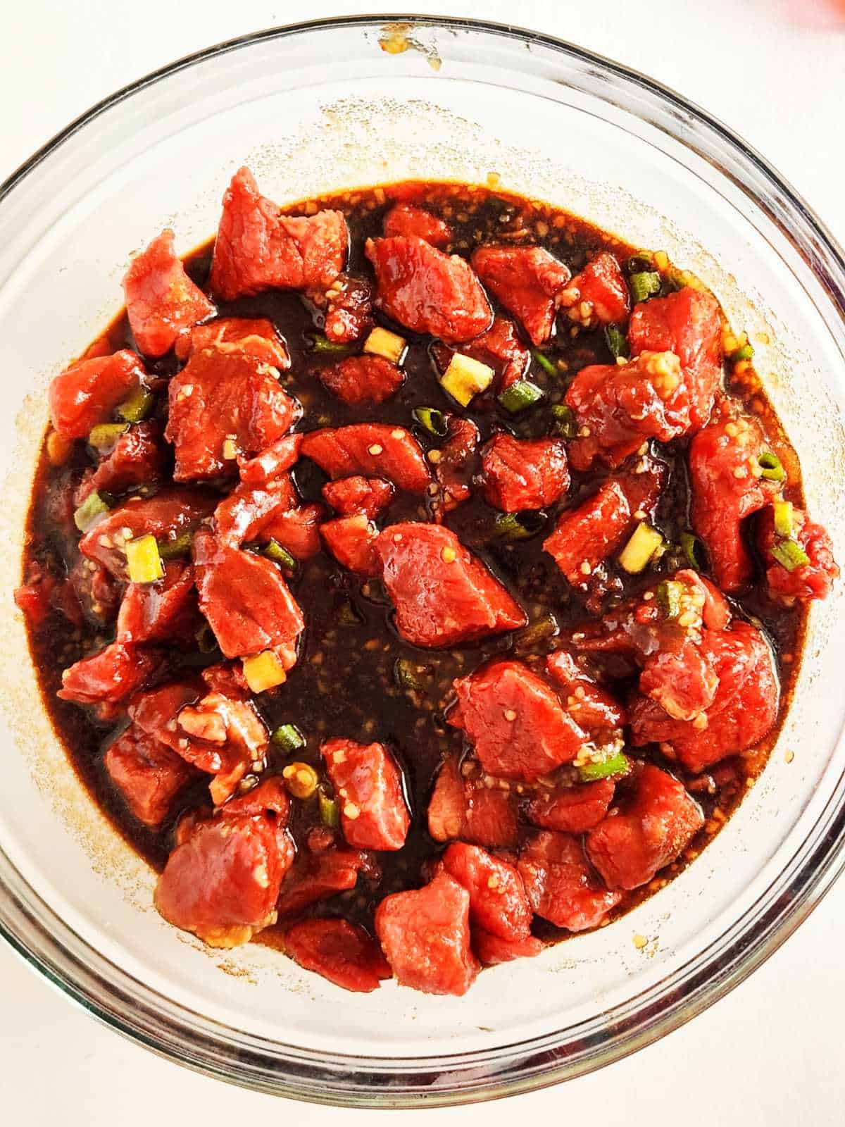 cubed beef marinating in bulgogi grilling sauce in a bowl.