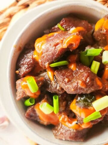 bowl of Korean beef bulgogi with Japanese yum yum sauce drizzled on top.