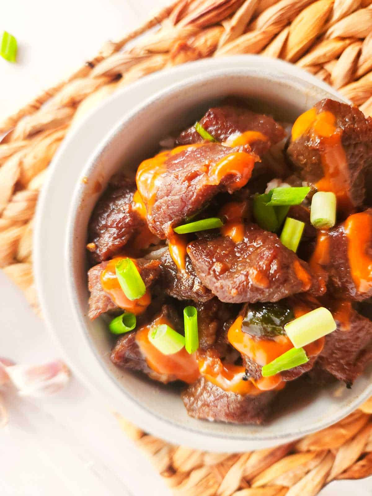 bowl of Korean beef bulgogi with Japanese yum yum sauce drizzled on top.