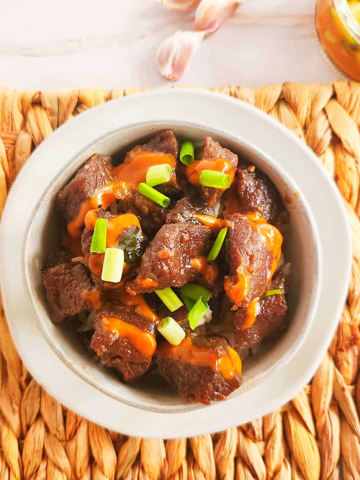 bowl of Korean beef bulgogi with Japanese yum yum sauce drizzled on top.