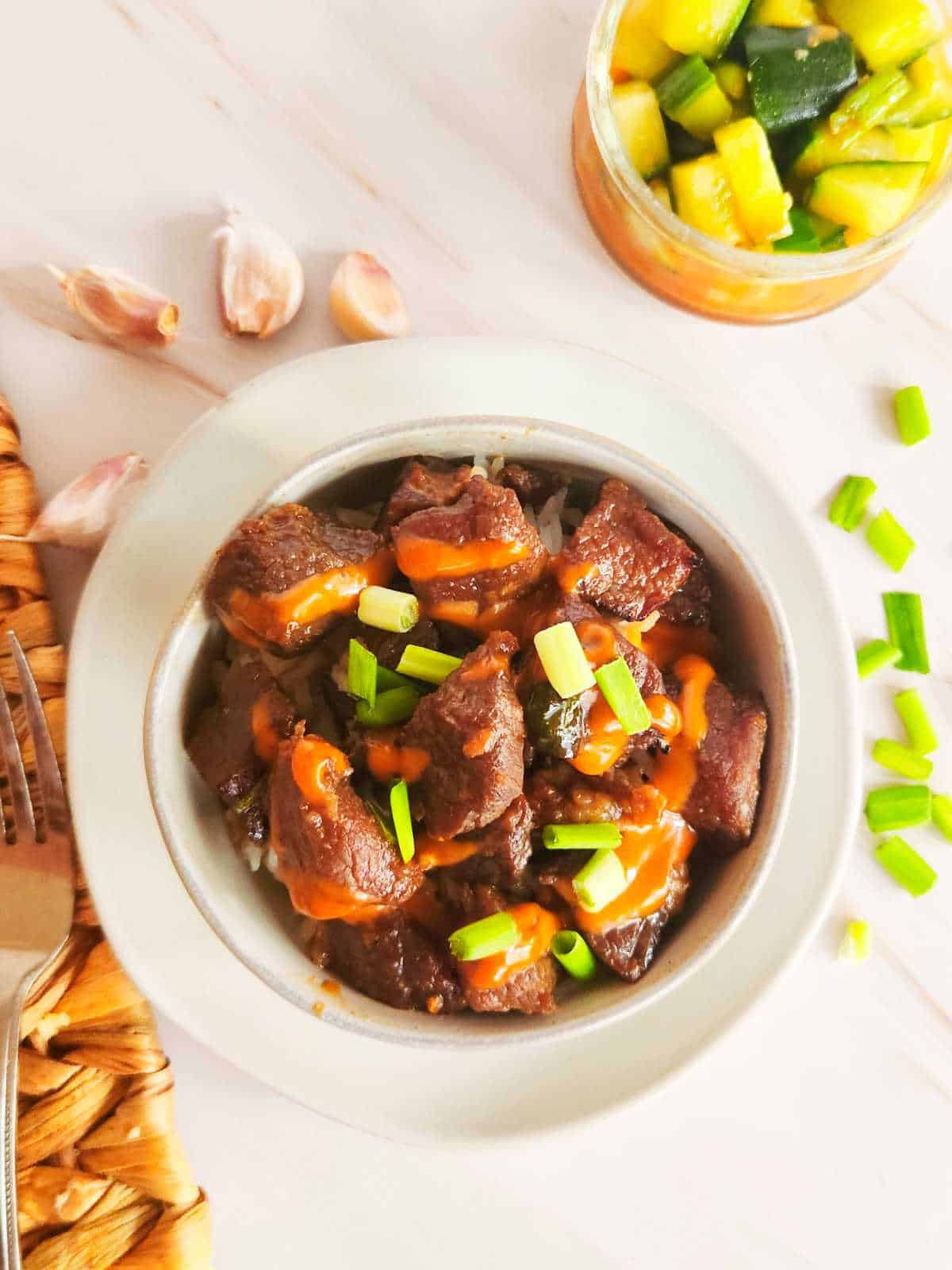 bowl of Korean beef bulgogi with Japanese yum yum sauce drizzled on top.