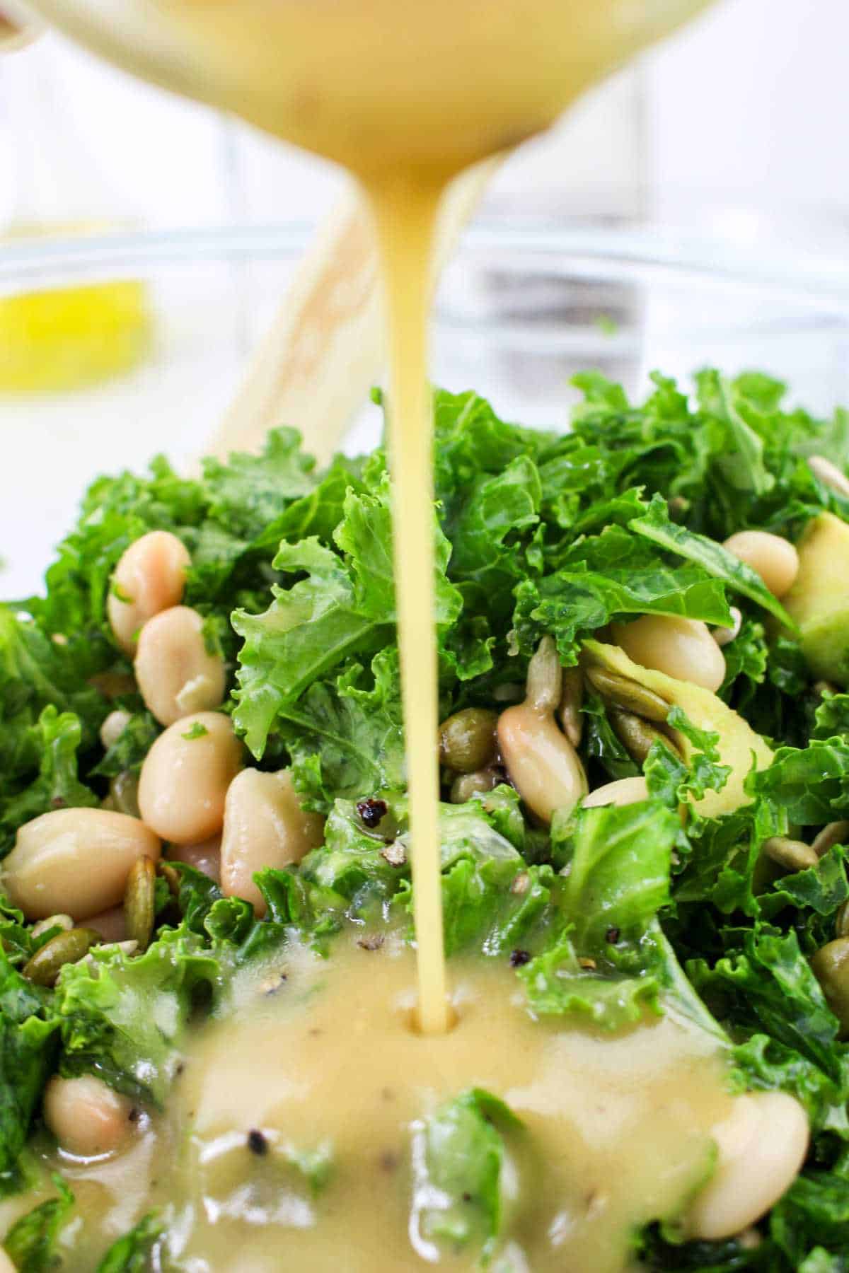 Drizzling lemon maple honey vinaigrette on salad.