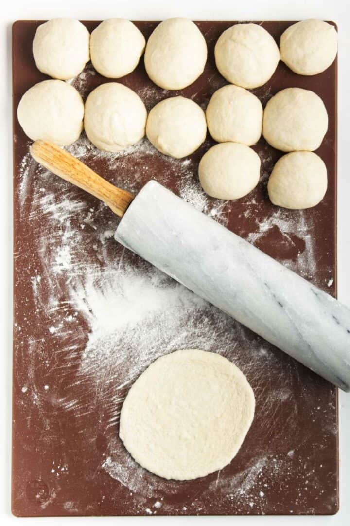 rolling balls of dough into mini pita breads.