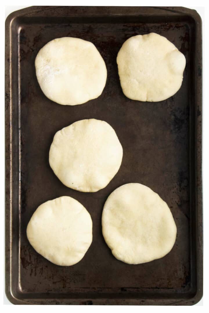 baked puffy pitas on a baking sheet.