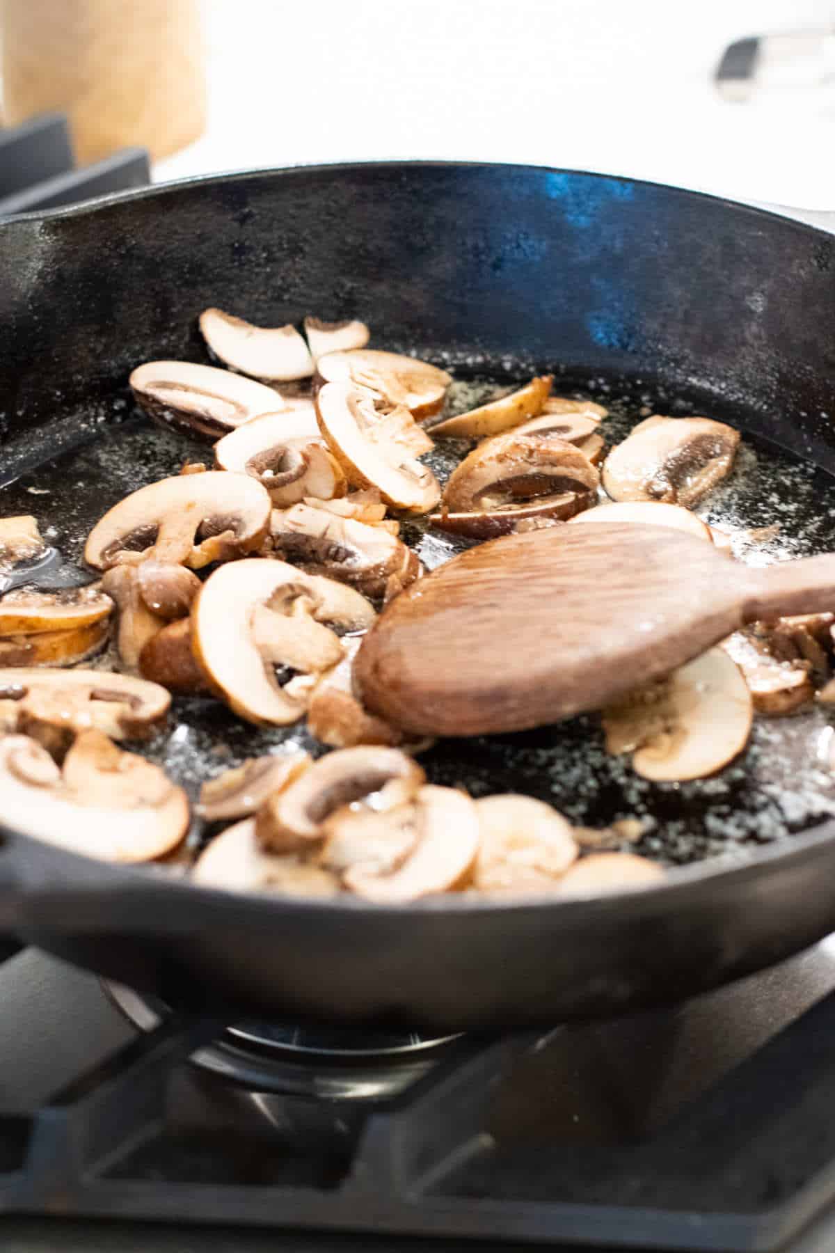 Cast iron skillet with mushrooms sauteing.