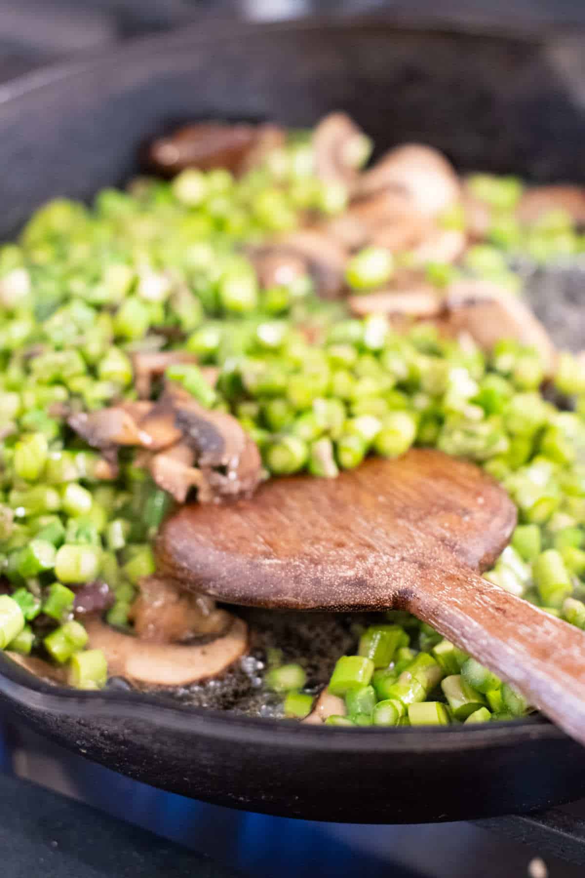 Cast iron skillet with asparagus and mushrooms sauteing.