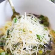 Parmesan topped mushrooms and asparagus topped pasta in a bowl.