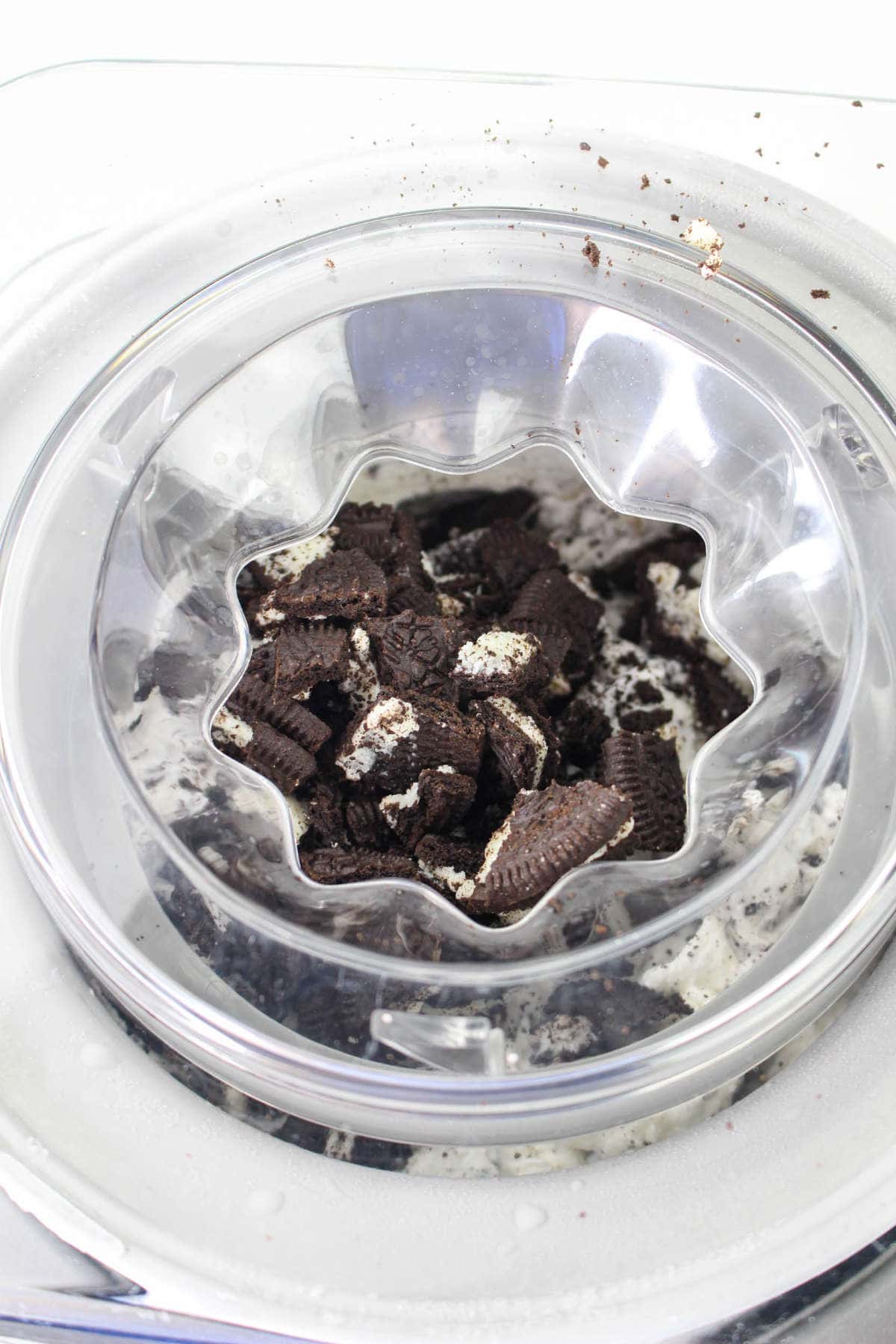 Adding broken Oreo cookies into the ice cream while churning in the Cuisinart Ice Cream Maker.