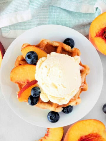 Dessert waffle with vanilla ice cream, peaches and blueberries.