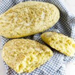 a full and a split loaf of semolina bread on a dish cloth.