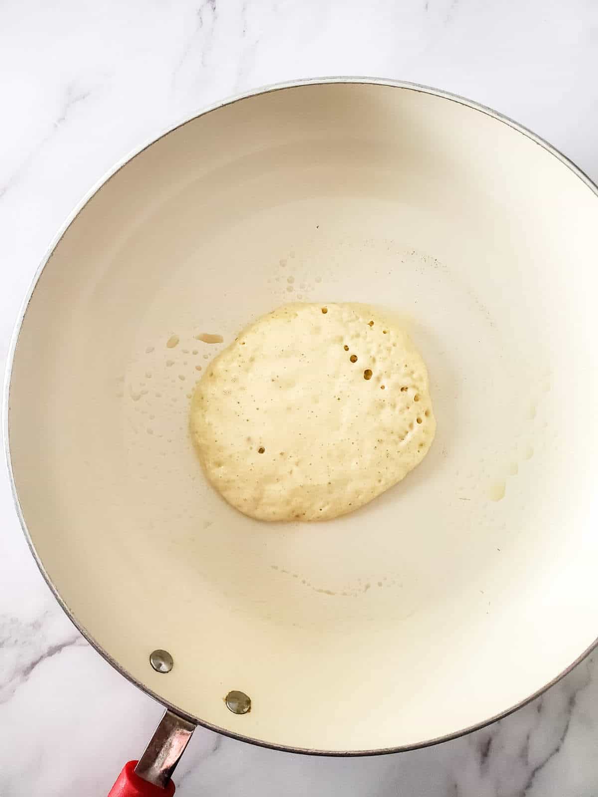 hot skillet with pancake browning and bubbles on the top.