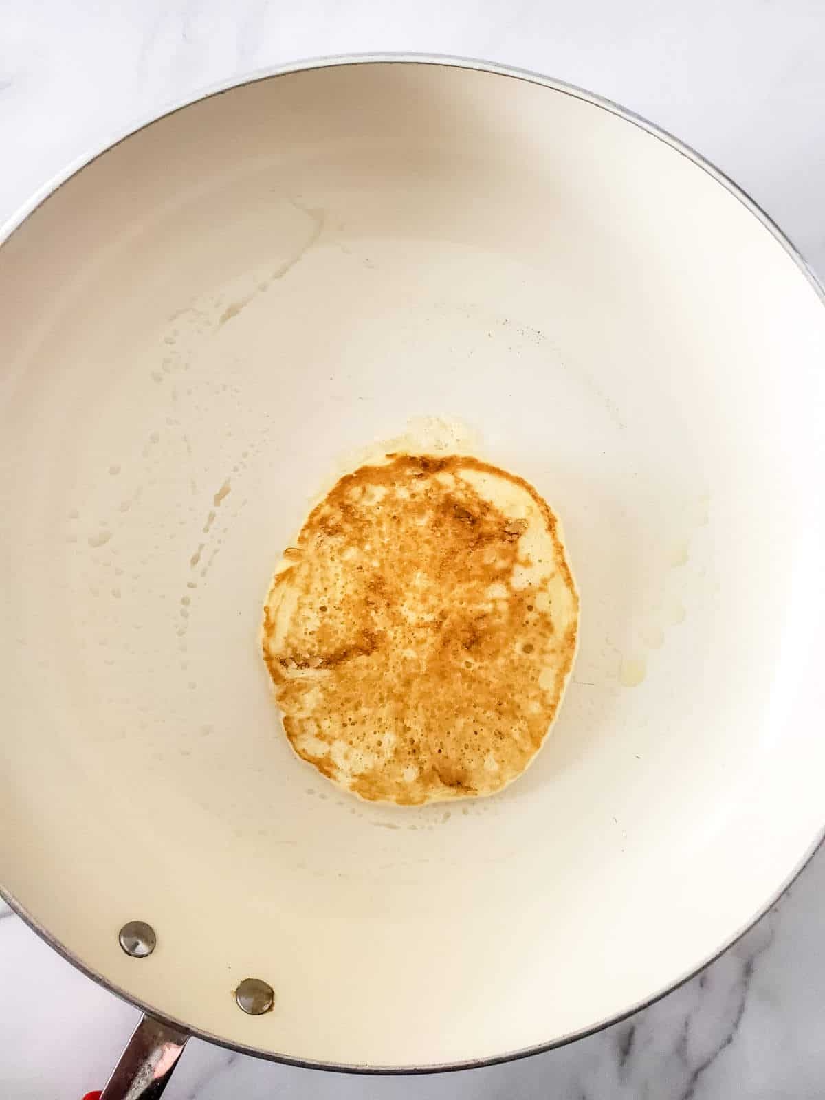 flipped golden brown pancake in a skillet.