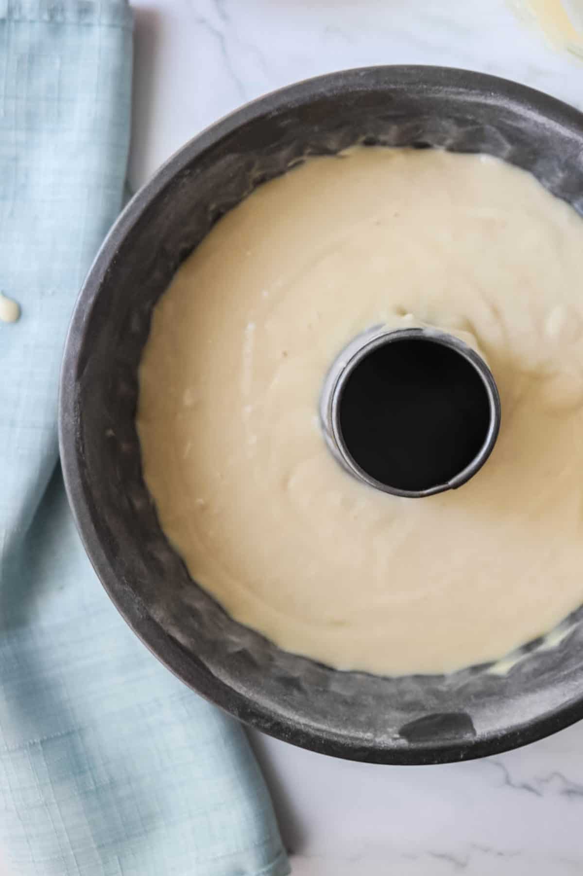 vanilla cake batter in a greased bundt pan ready to bake.