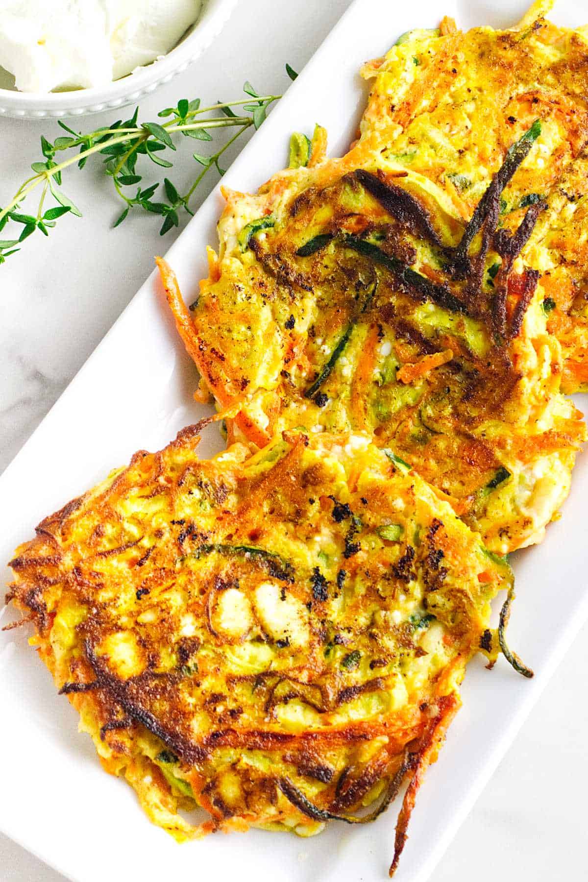 serving platter with zucchini carrot latkes with feta cheese.