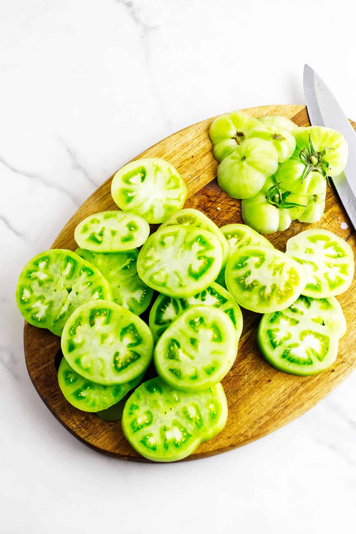 Sliced green tomatoes and whole green tomatoes.