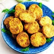 A blue plate filled with golden, crispy fried green tomatoes slices.