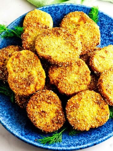 A blue plate filled with golden, crispy fried green tomatoes slices.