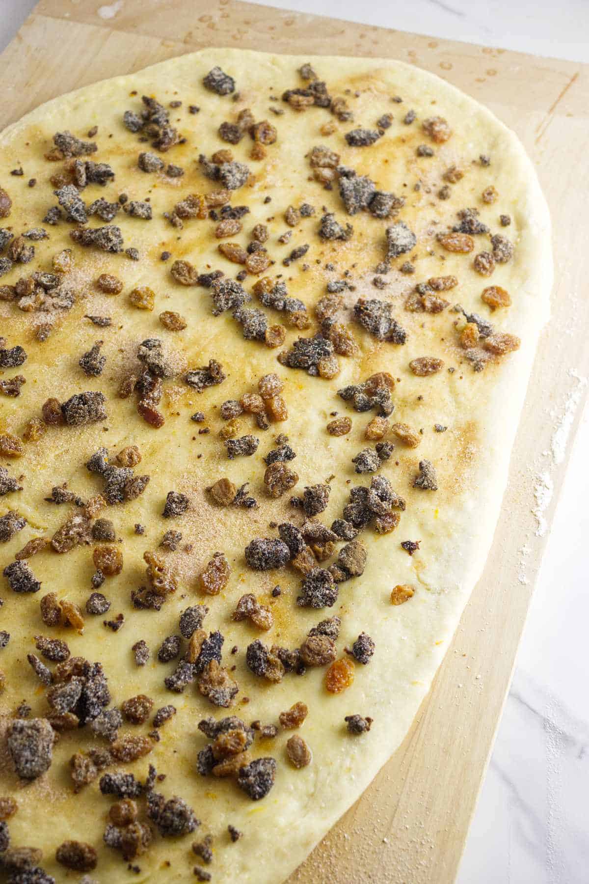 Rosca de Reyes dough brushed with butter and sprinkled with cinnamon sugar, raisins, and nuts.