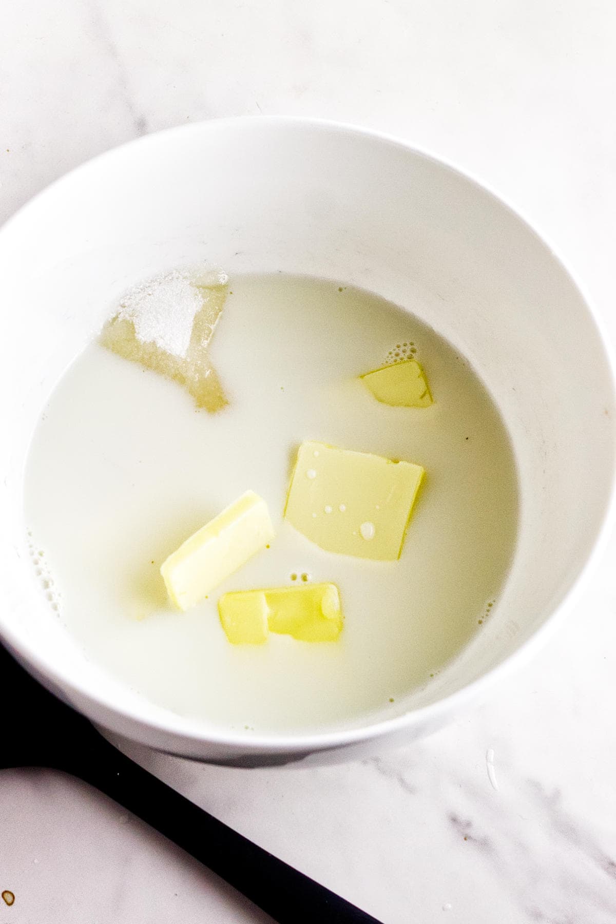 Milk, butter, sugar, and salt warming in a bowl for enriched Rosca de Reyes dough.