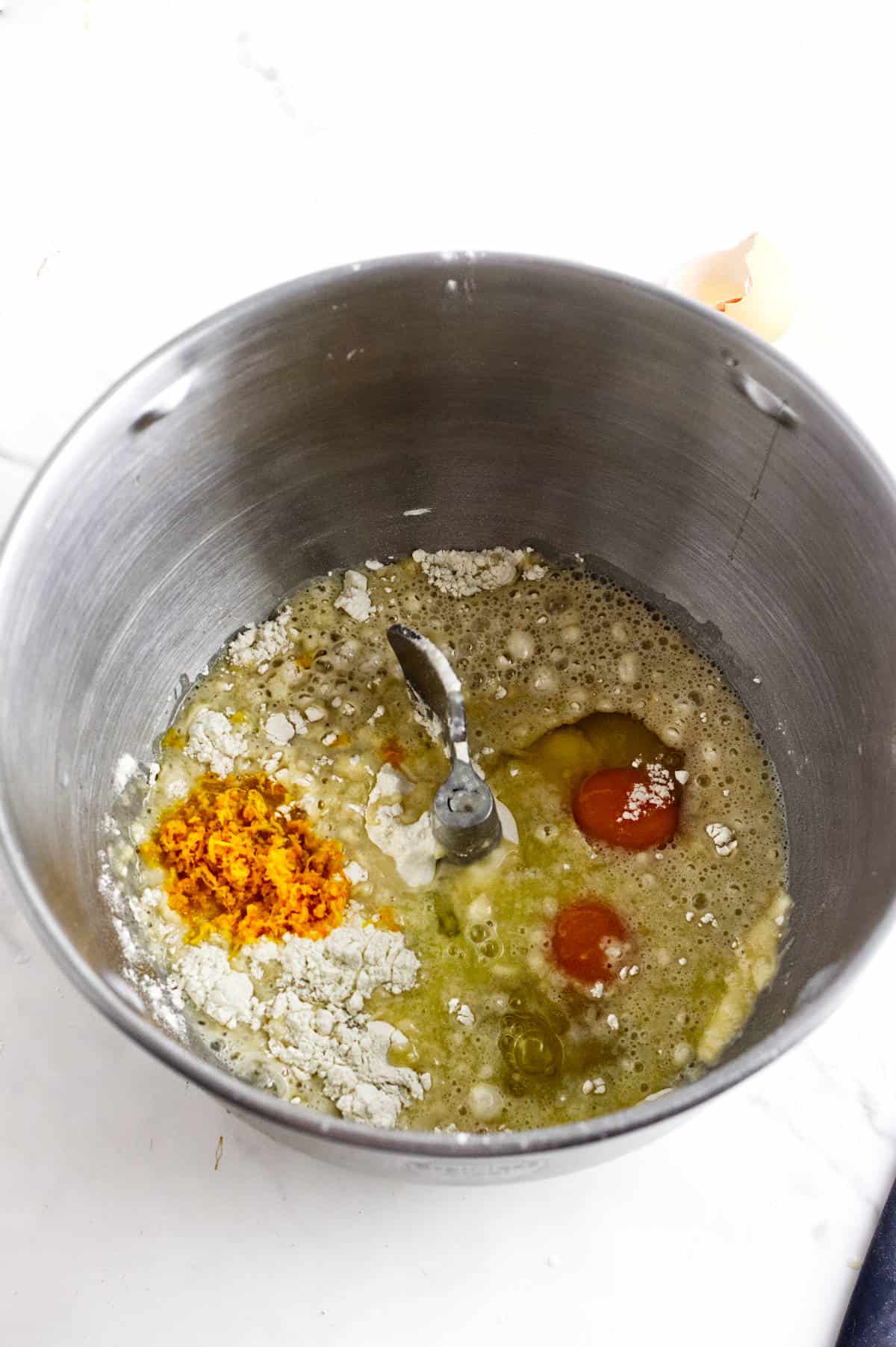 Flour, eggs, orange zest, vanilla, and yeast mixture combined for Rosca de Reyes dough.