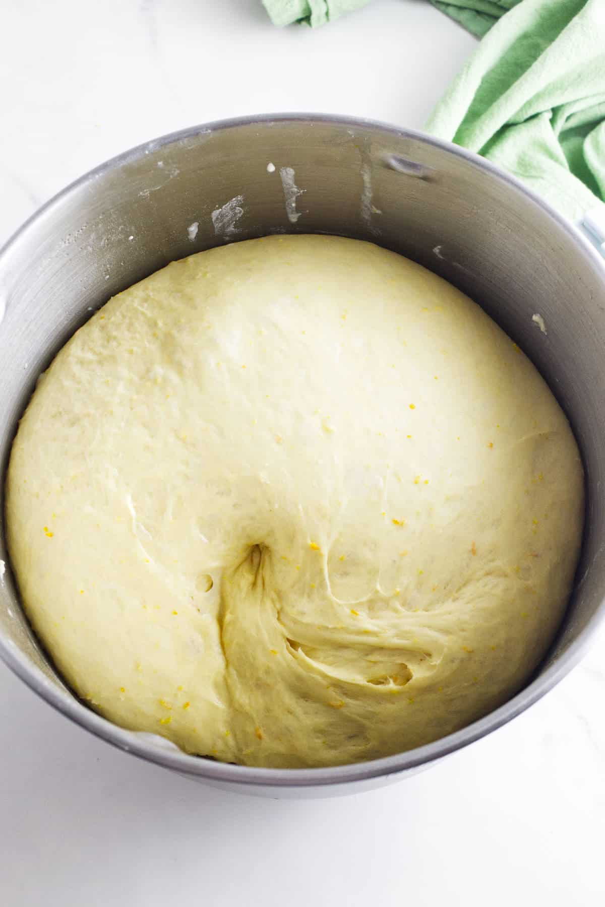 Risen Rosca de Reyes dough doubled in size in a stainless steel bowl.